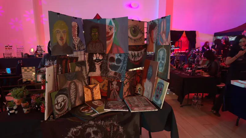 Detalle de la rejilla con pinturas y esculturas pequeñas de arcilla sobre la mesa del stand