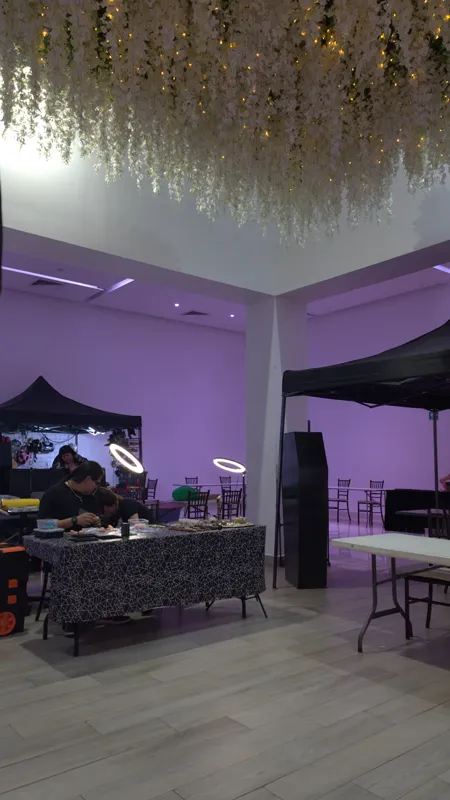 Salón con candelabro de flores colgantes y carpas de expositores en luz morada