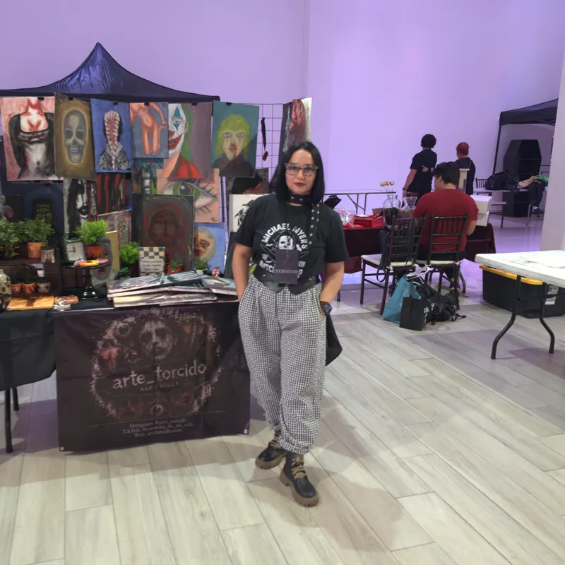 Sara Villa en su stand de la Expo Gótica MTY, con el salón en luz morada